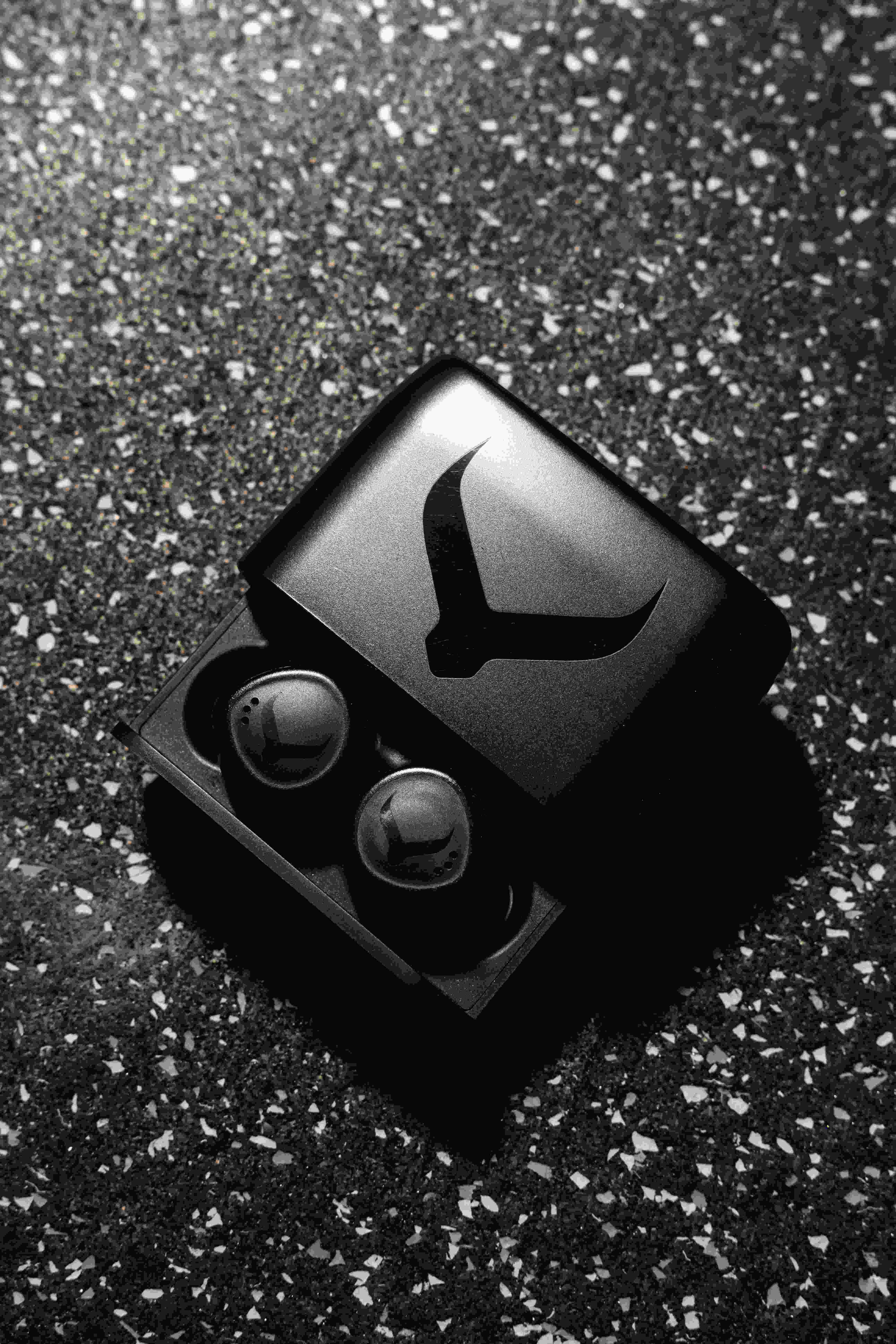 Black Tzuka TZ7 Ultra earbuds in their open charging case on a gym floor