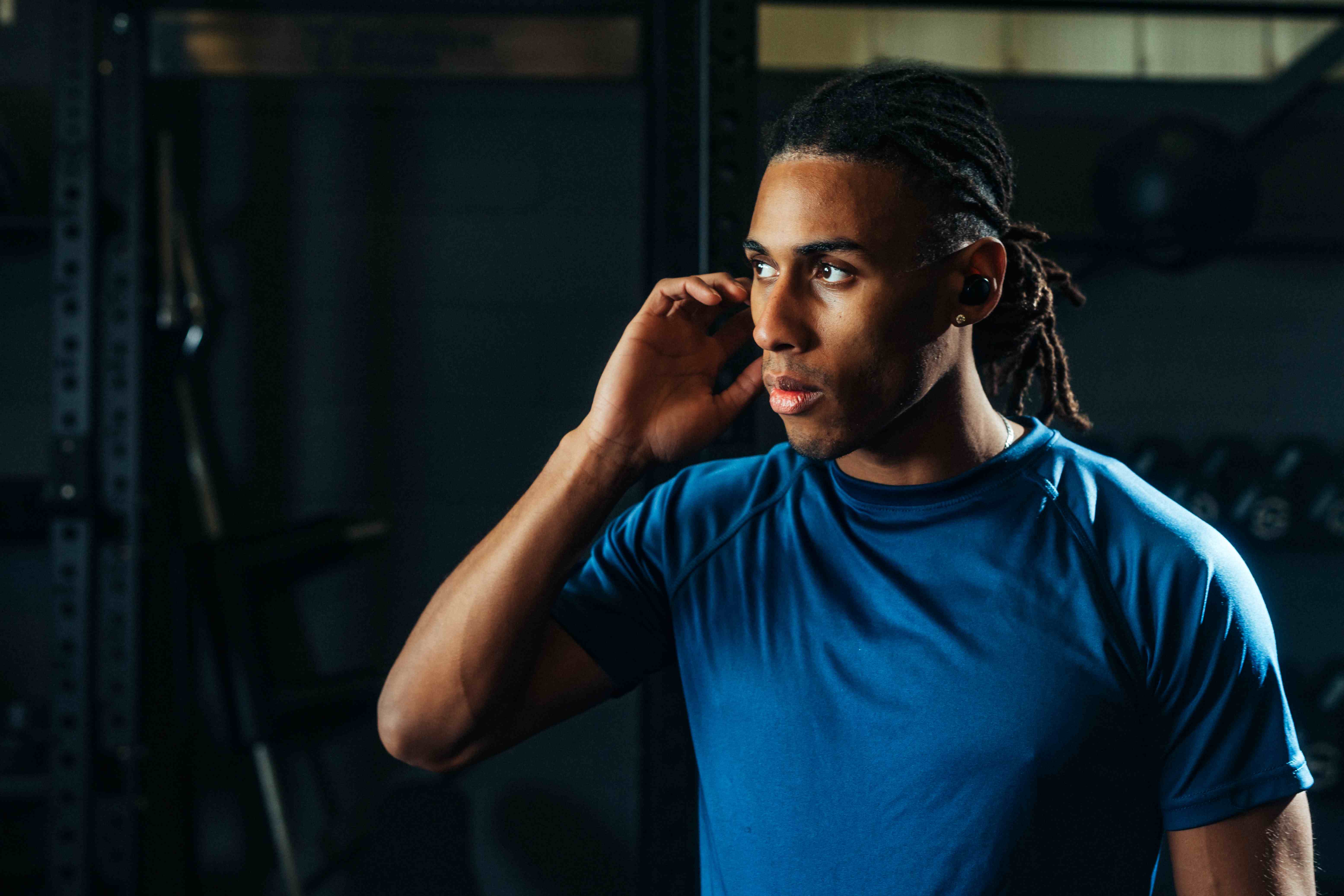 Athlete tapping earbud to change gym music without a phone